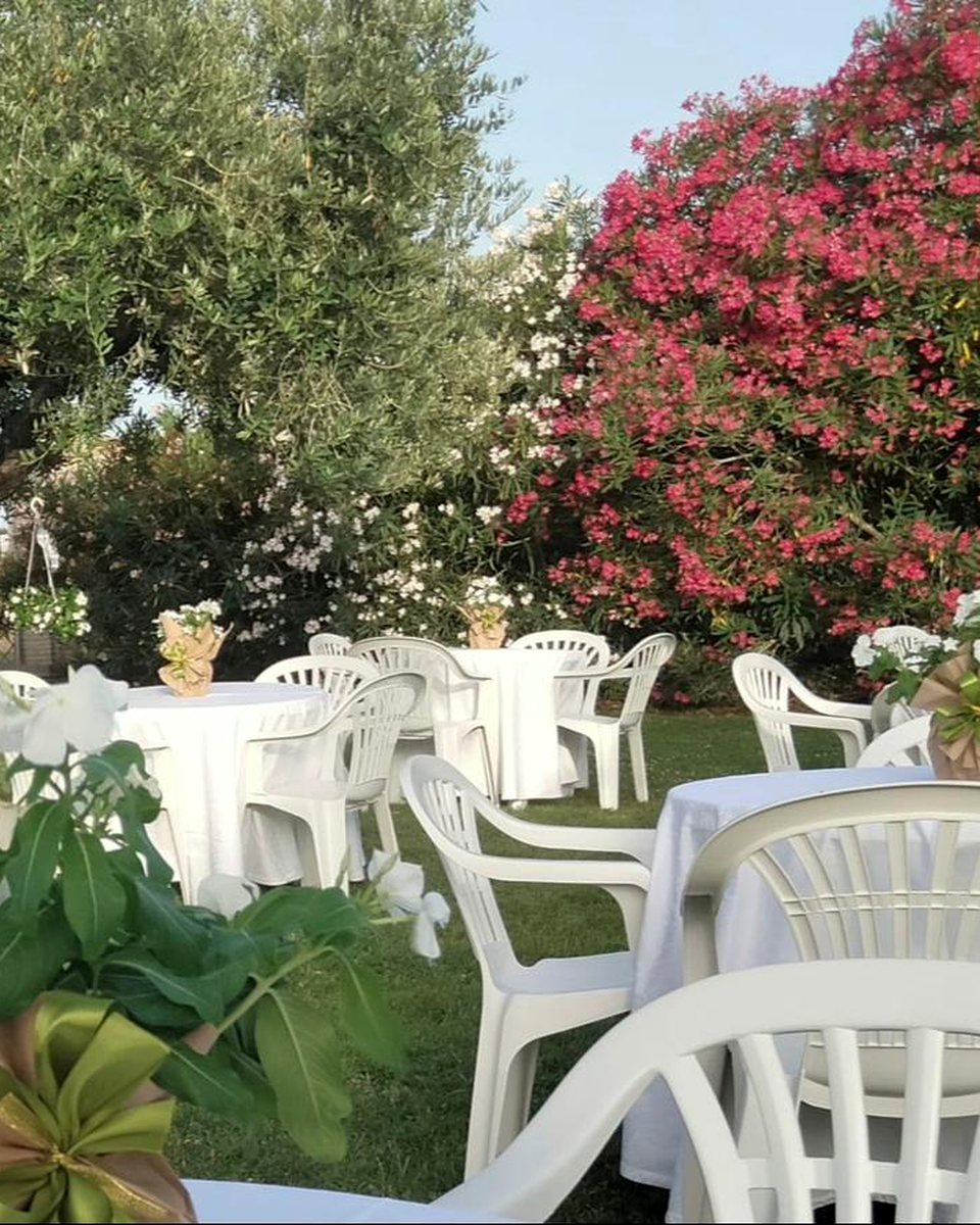 Tavoli allestiti in giardino tra verde e fiori